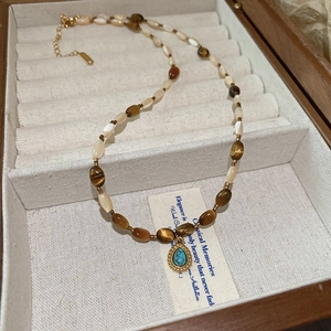 Detail of beaded tiger eye necklace with turquoise pendant in a wooden jewelry box
