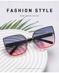 Detailed shot of cat-eye sunglasses with purple gradient lenses on a textured white pedestal