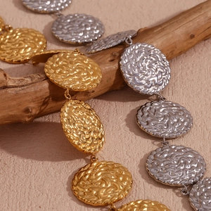 Dettaglio di dischi in metallo martellato in finiture oro e argento con trama intrecciata