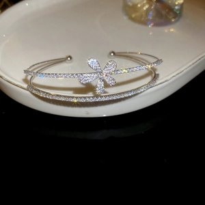 Macro detail of silver floral bangle with zircon petals on elegant porcelain display