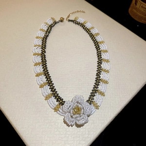 Detailed view of hand-woven beaded flower necklace with white petals and gold clasp