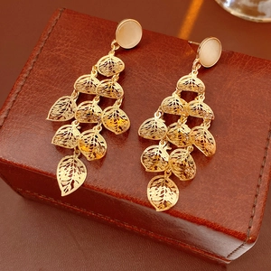 Macro shot of gold-plated hollow leaf tassel earrings with white opal cat-eye stone