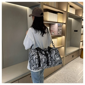 Detail view of zebra print travel bag featuring front pockets and adjustable shoulder strap