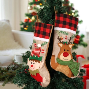 Set di due calze di Natale con elfo e renna appese a un albero decorato