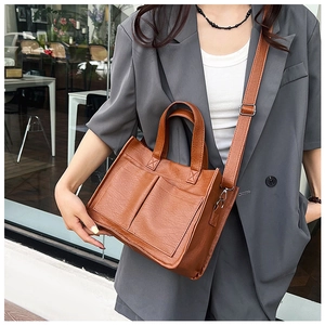 Detail of vintage brown PU leather tote bag with functional front pockets and strap