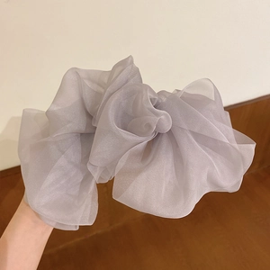 Detail of grey organza bow hair clip showing translucent pleated texture and large size