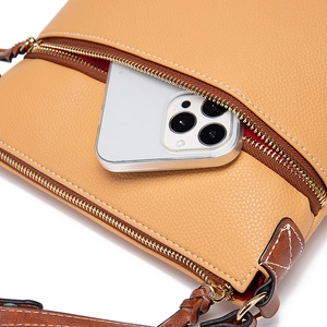 Detail of yellow lychee leather bag with metal zipper pocket holding a smartphone