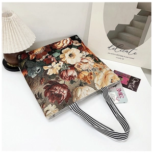 Detail of 3D ethnic floral embroidery on a canvas tote with striped woven handles