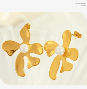 Détail de boucles d'oreilles fleur dorées avec perles sur un récipient en verre