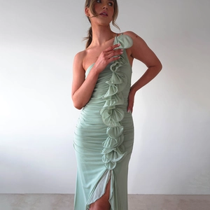 Détail d'une robe vert clair à une épaule avec des volants et une fente haute