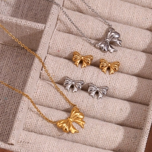 Macro detail of gold and silver bow pendant necklaces and earrings set in gift box