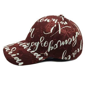 Detail of dark red distressed baseball cap with white cursive letter print and textured fabric