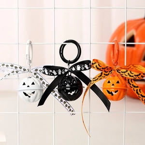 Halloween pumpkin bell keychains in white black and orange with ribbon bows on metal grid