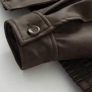 Detail of dark brown faux suede jacket cuff with resin button and elastic stitching