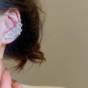 Detail of silver vine ear cuff with zircon petals and pearls worn on a female ear