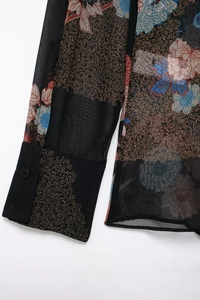 Close-up of vintage chiffon shirt featuring floral paisley patterns and buttoned cuffs