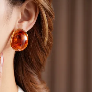 Vintage amber resin earrings with gold edges shown on model in a stylish close-up shot