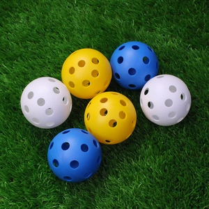 Macro shot of 72mm 26-hole pickleballs in yellow, blue and white on green turf background