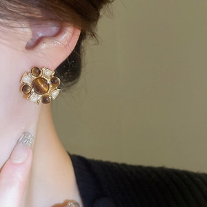 Detail view of a vintage round earring with brown resin stone and faux pearl beads