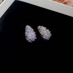 Macro shot of rose gold waterdrop stud earrings with sparkling pavé zircons on black velvet