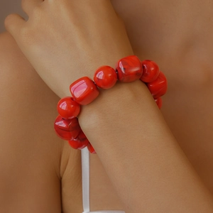 Detail of red acrylic beaded bracelet featuring chunky square and round beads on wrist