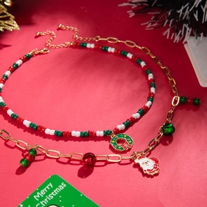 Detail of Christmas beaded necklace with wreath and Santa Claus charms on festive red backdrop