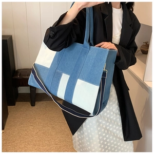 Detail of color-block denim tote bag showing mixed blue patchwork and sturdy handles