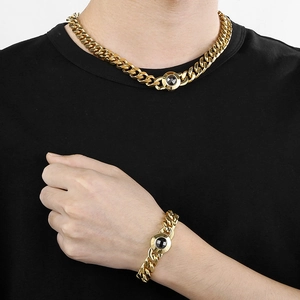 Close-up of men's gold Cuban chain necklace and bracelet with black gemstone accents