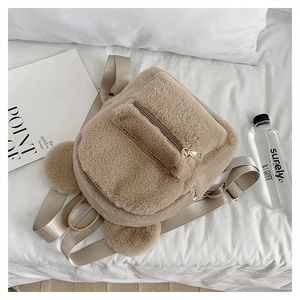 Detail of a beige plush backpack featuring cute 3D bear ears on a cozy white background