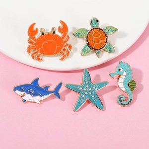 Detailed close-up of colorful ocean animal enamel pins including crab, turtle, and shark