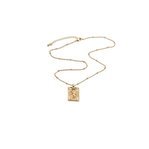 Detail view of a gold square medallion pendant with embossed pattern on a beaded chain