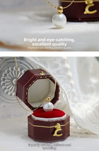 Detailed close-up of a white pearl pendant on a delicate 18K gold chain in a vintage red box