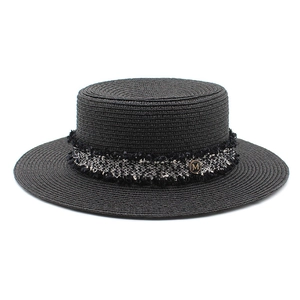 Detail of black straw boater hat with tweed ribbon and golden M logo emblem
