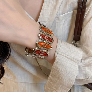 Close-up of vintage silver bracelet with orange enamel and geometric fretwork pattern