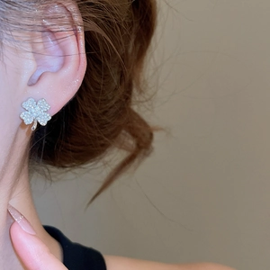 Close-up of sparkling silver clover stud earrings featuring micro-set zircon stones on model