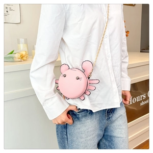 Pink crab-shaped crossbody bag with gold chain strap worn by a model in a casual outfit