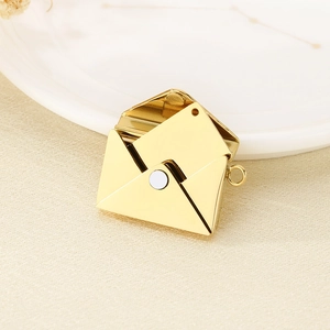 Macro shot of an openable gold envelope pendant with an inner card on a ceramic tray