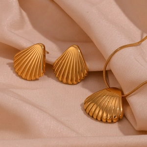 Vista dettagliata di orecchini e collana a conchiglia placcati oro su seta champagne