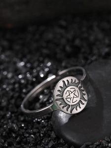 Macro detail of silver stainless steel star ring on stone with sun pattern engraving