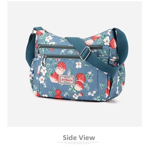 Macro view of blue nylon crossbody bag featuring floral print and zipper compartments