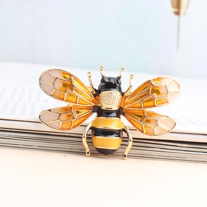 Elegant gold-tone bee brooch with yellow enamel wings and crystal accents on book page