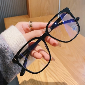 Macro shot of stylish square black glasses with gold D-shaped logo and blue light filter lens