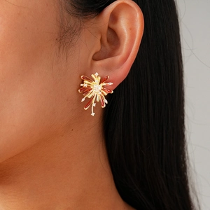 Elegant gold fireworks stud earrings with red enamel and zircon on a model