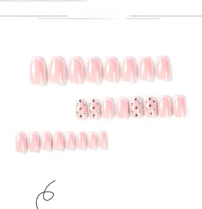 Macro detail of pink French press-on nails with white tips and sparkling rhinestone accents
