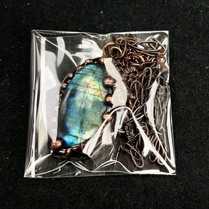 Detail of natural labradorite stone pendant with vintage bronze wire wrap and layered chain