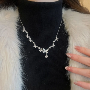 Close-up of silver butterfly necklace with zircon pendants on model with black sweater