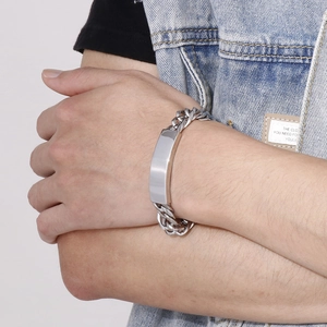 Close-up of a silver stainless steel curb chain bracelet with a blank bar on a male wrist