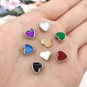 Macro shot of 8-color enamel heart spacer beads with silver metallic edges held in hand