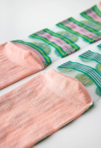 Detail view of sheer mesh socks with green floral patterns and pink knitted toe sections