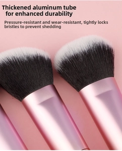 Detail of pink metal ferrule and dense bicolour synthetic bristles on makeup brushes